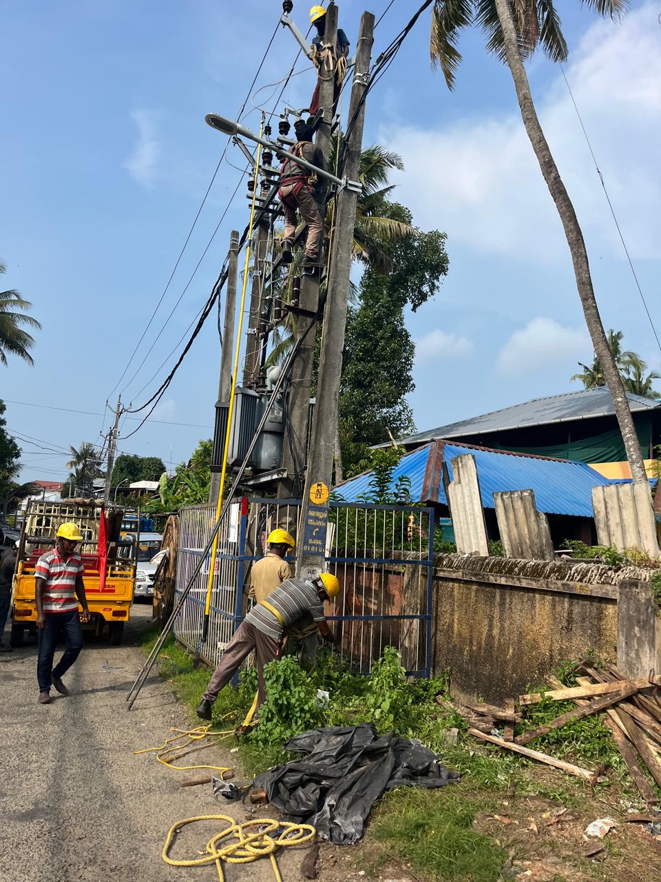 Linemen carrying out light post and electrical line work on a pole